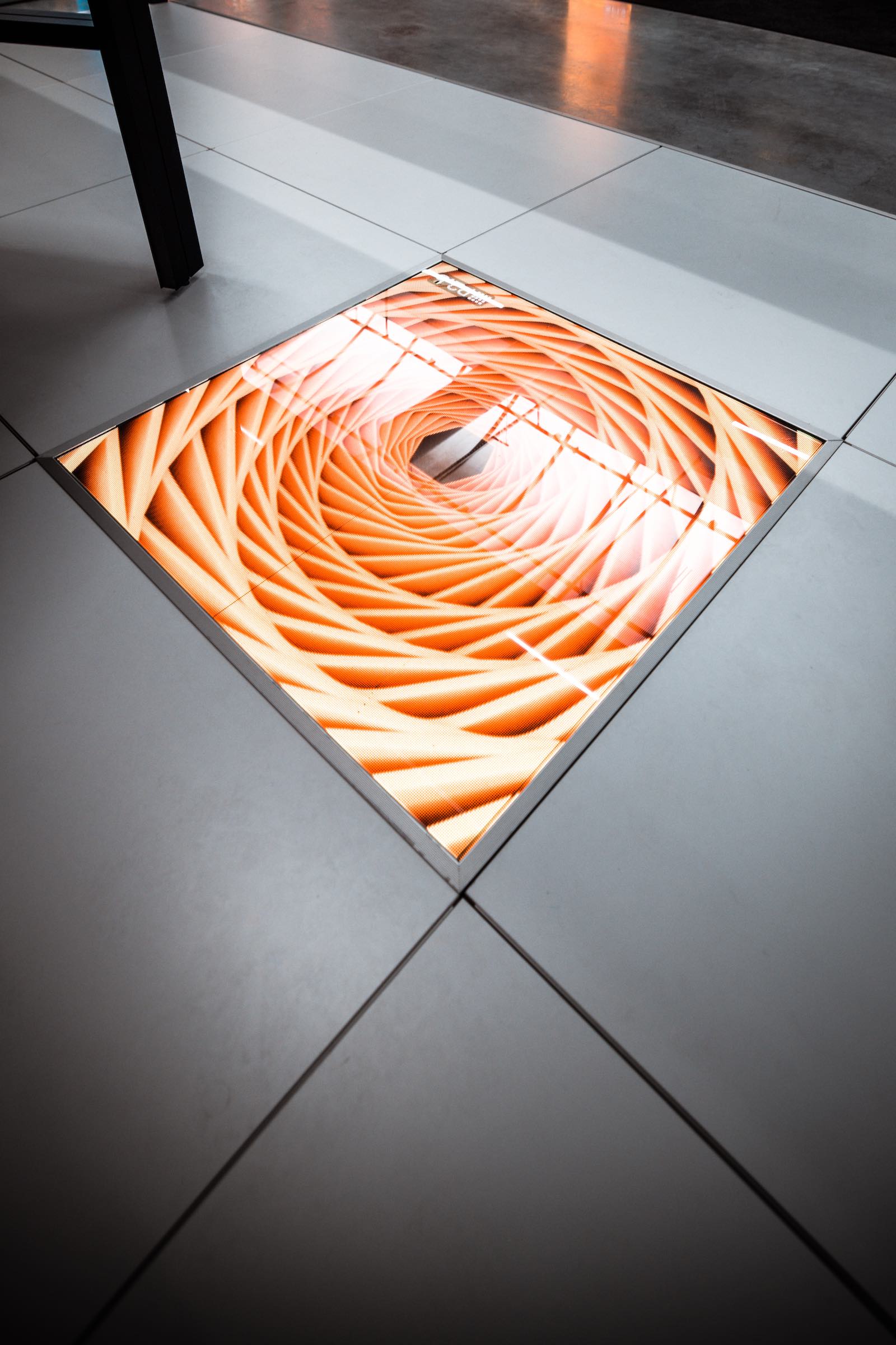 In den Boden eingelassenes LED-Panel mit leuchtender Grafik auf einem Messestand.