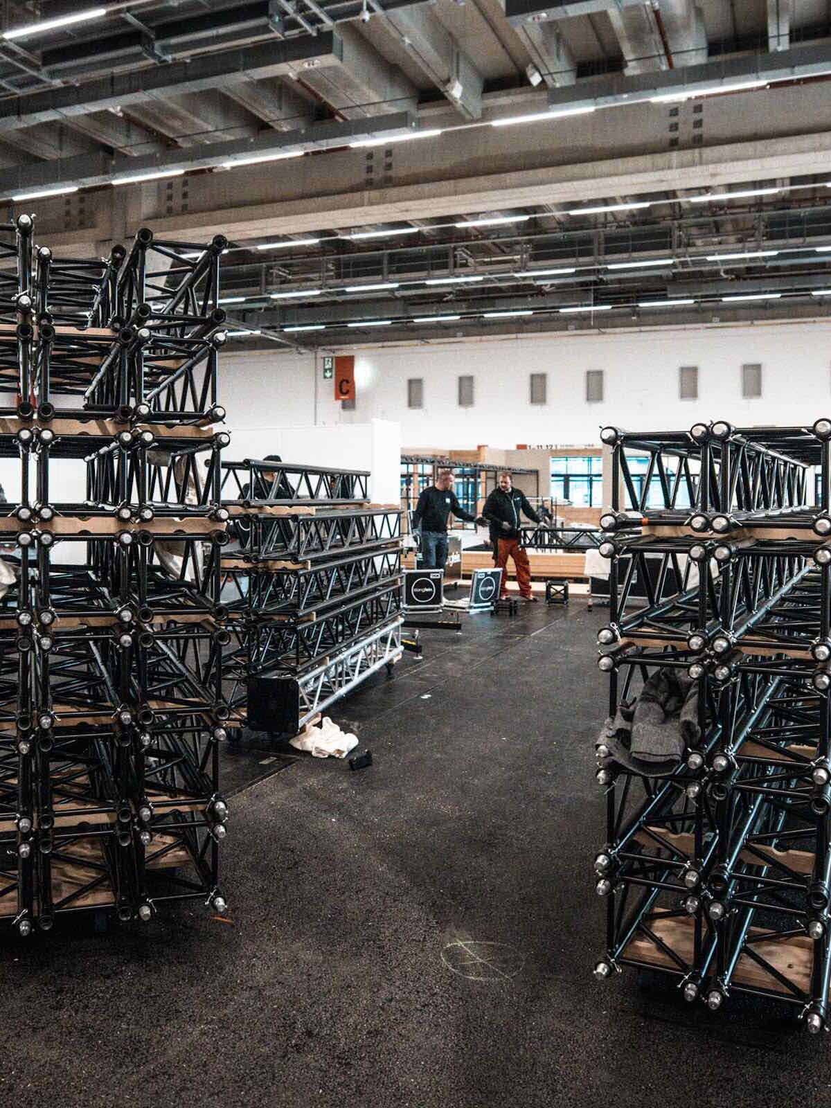 Messehalle im Aufbau mit gestapelten Traversen-Elementen und Technikcases.