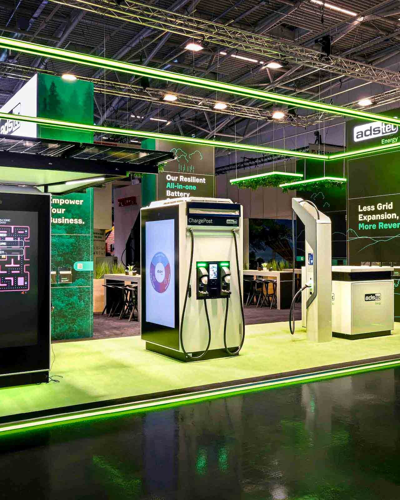 Messestand von adstec Energy mit grünem LED-Rahmen, Wall-Branding und E-Mobility-Ladeequipment.