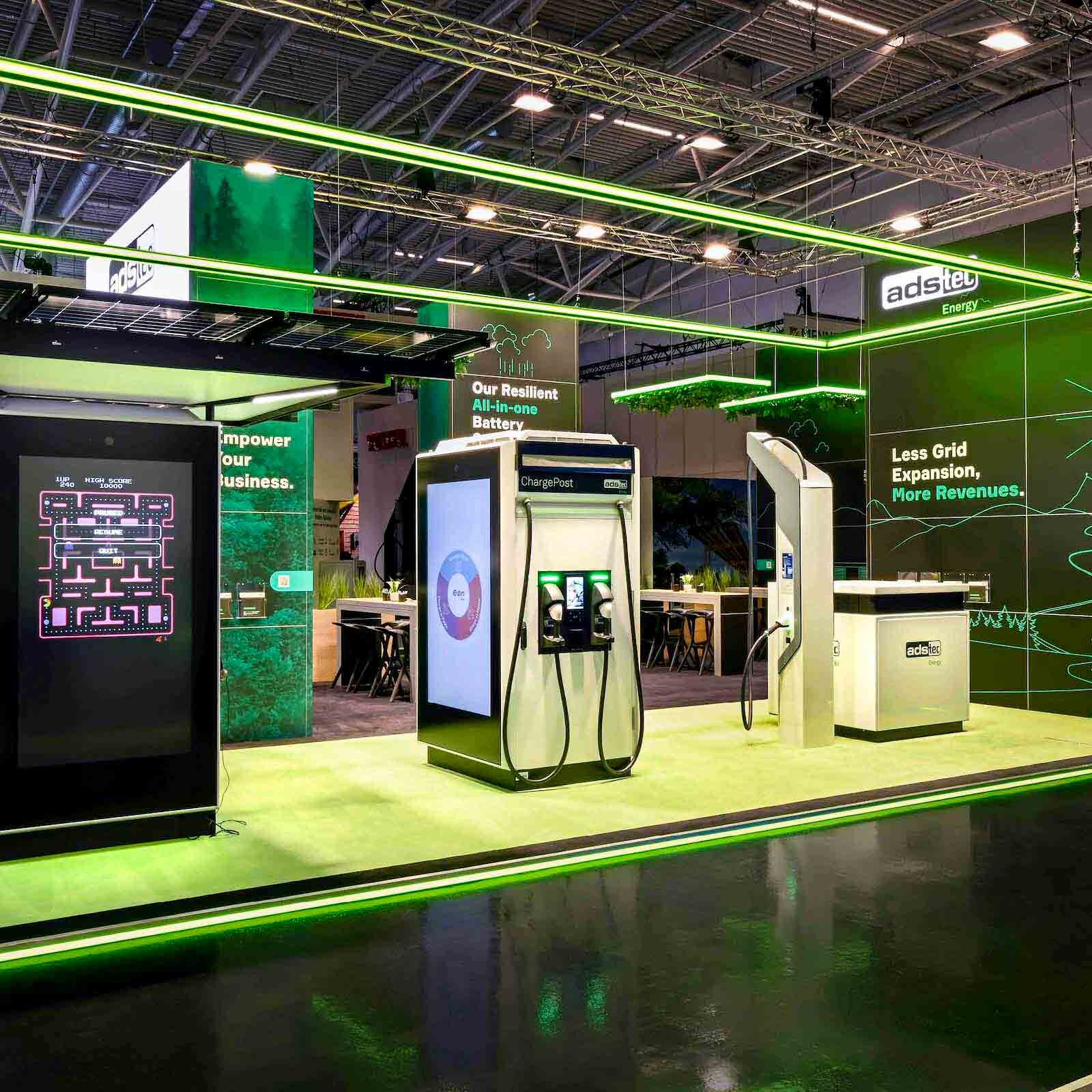 Messestand von adstec Energy mit grünem LED-Rahmen, Wall-Branding und E-Mobility-Ladeequipment.