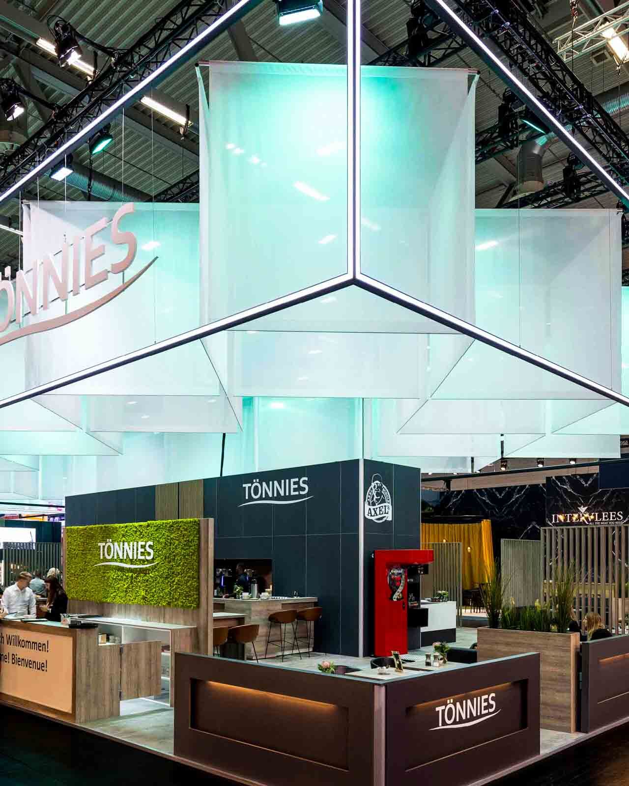 Großer Tönnies Messestand mit LED-Rahmen/Deckensegel, Rigging, Empfangstheke und Lounge-Bereichen.