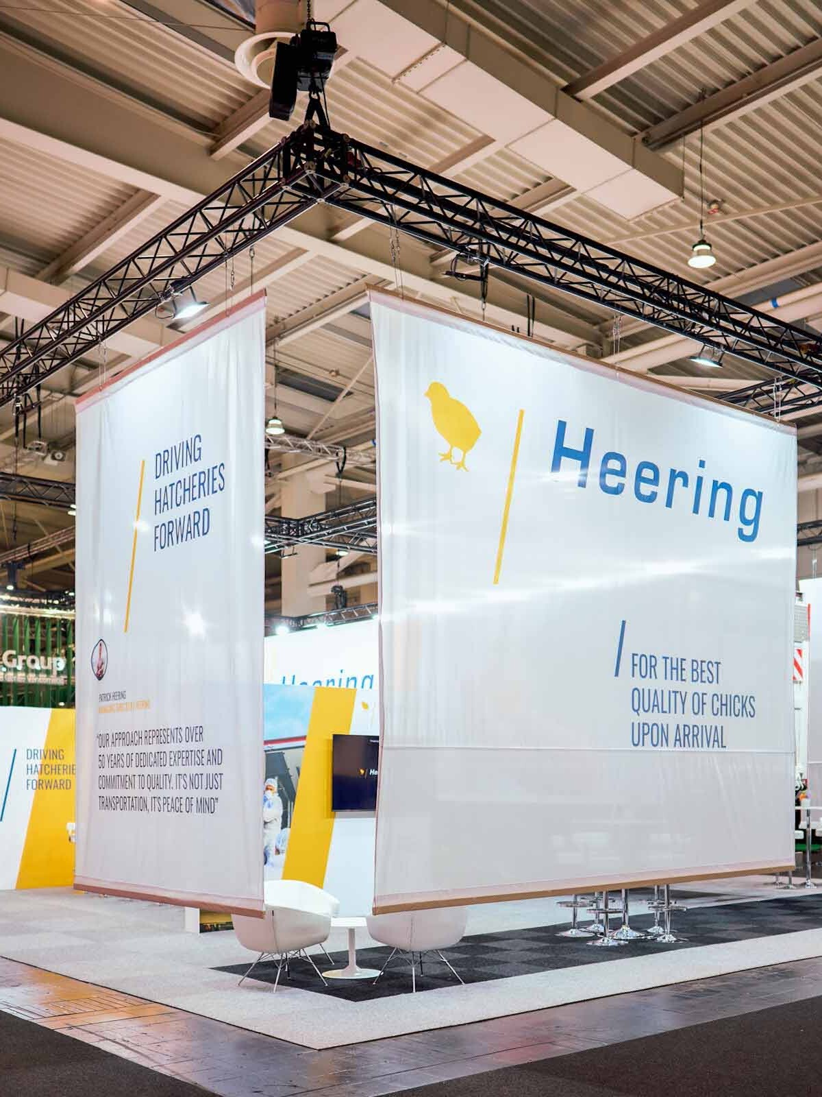 Großer Messestand mit Traversensystem, Bannern und Beleuchtung in Messehalle für professionellen Messebau