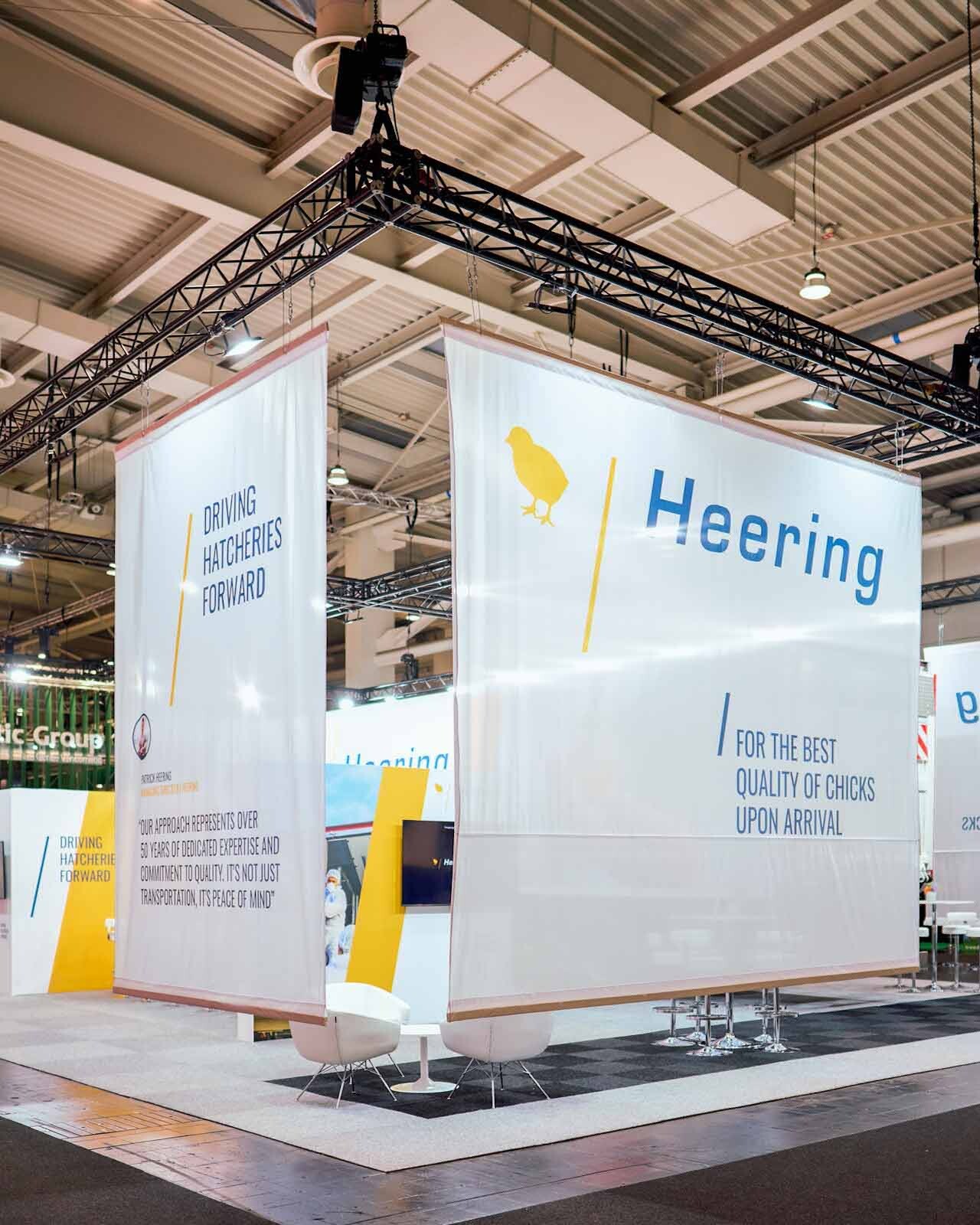 Großer Messestand mit Traversensystem, Bannern und Beleuchtung in Messehalle für professionellen Messebau
