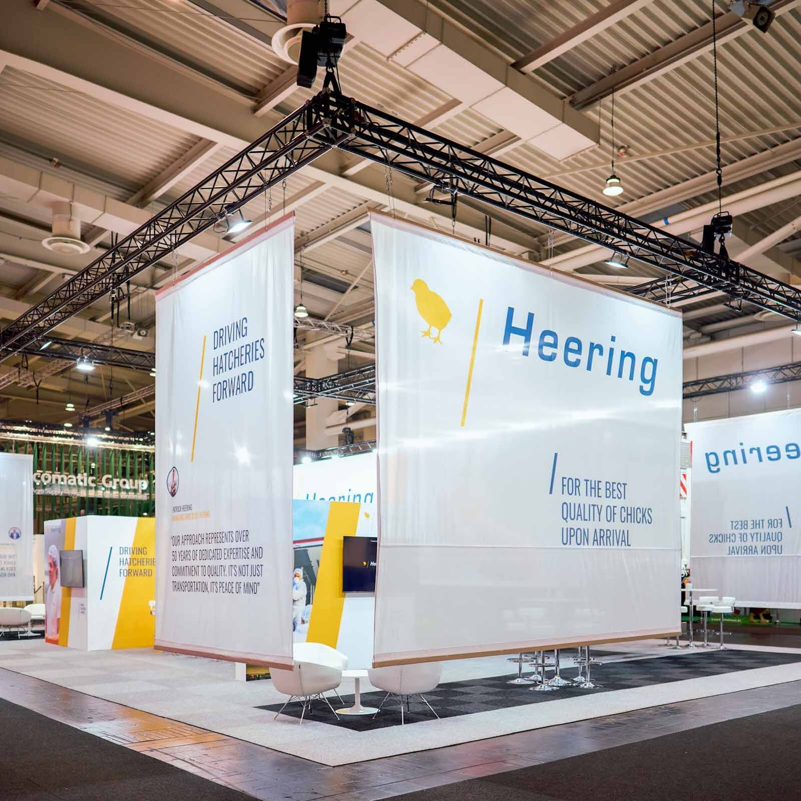 Großer Messestand mit Traversensystem, Bannern und Beleuchtung in Messehalle für professionellen Messebau