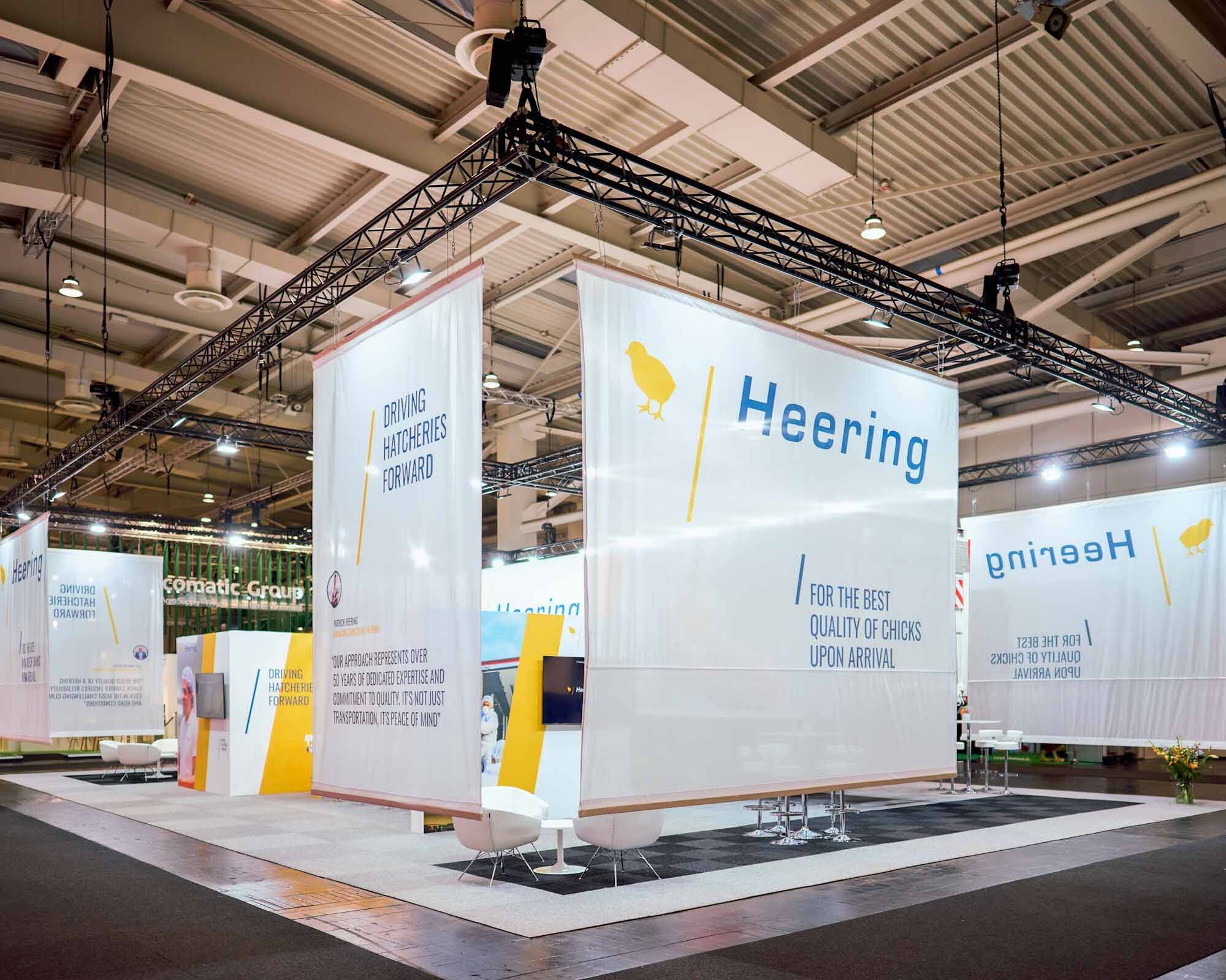 Großer Messestand mit Traversensystem, Bannern und Beleuchtung in Messehalle für professionellen Messebau