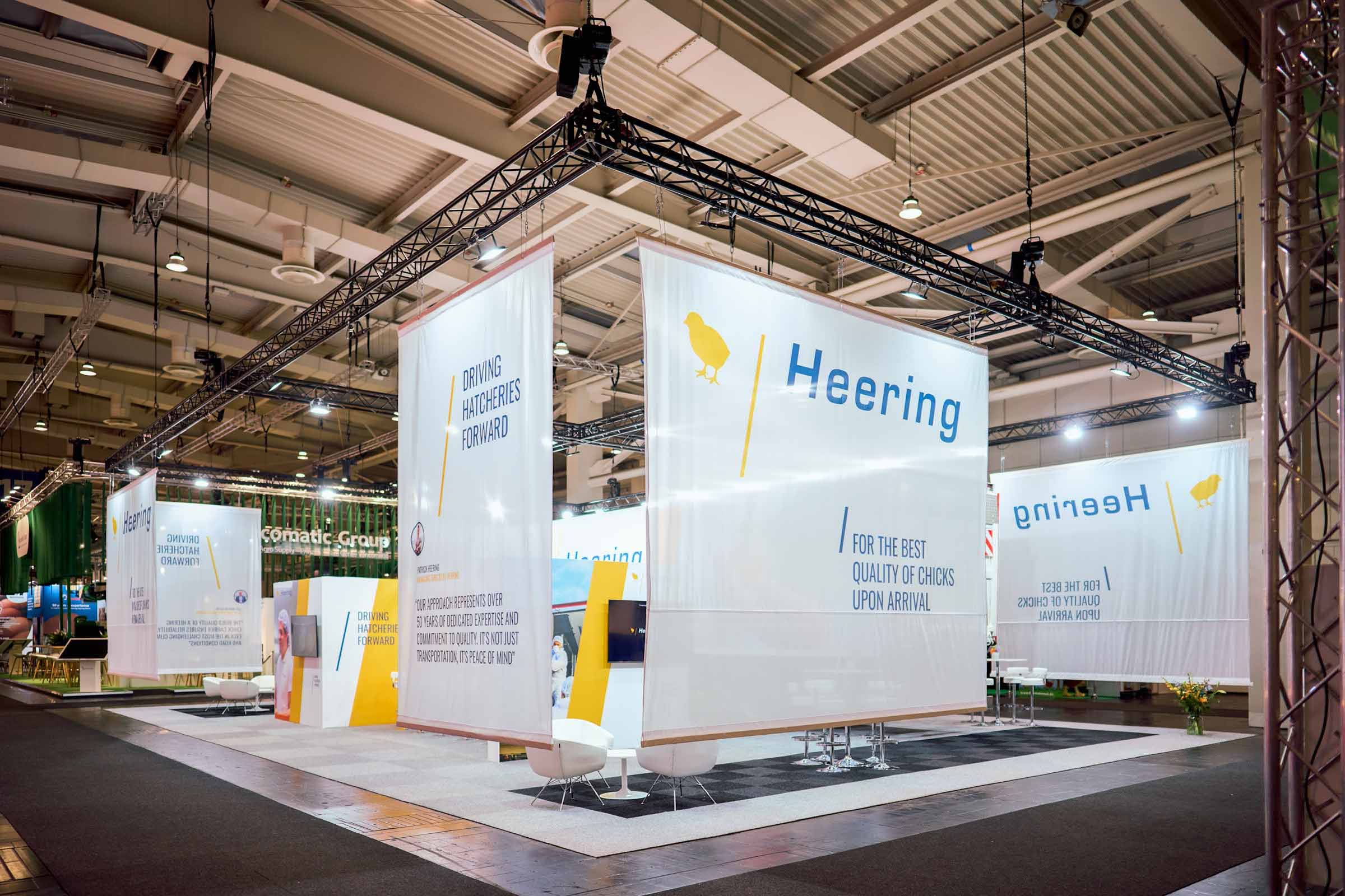 Großer Messestand mit Traversensystem, Bannern und Beleuchtung in Messehalle für professionellen Messebau