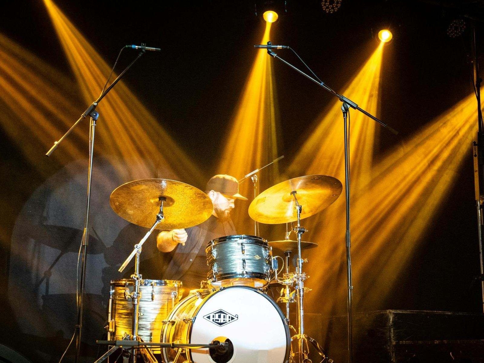 Schlagzeug auf Bühne mit gelber Konzertbeleuchtung und professioneller Lichttechnik bei einem Live-Event