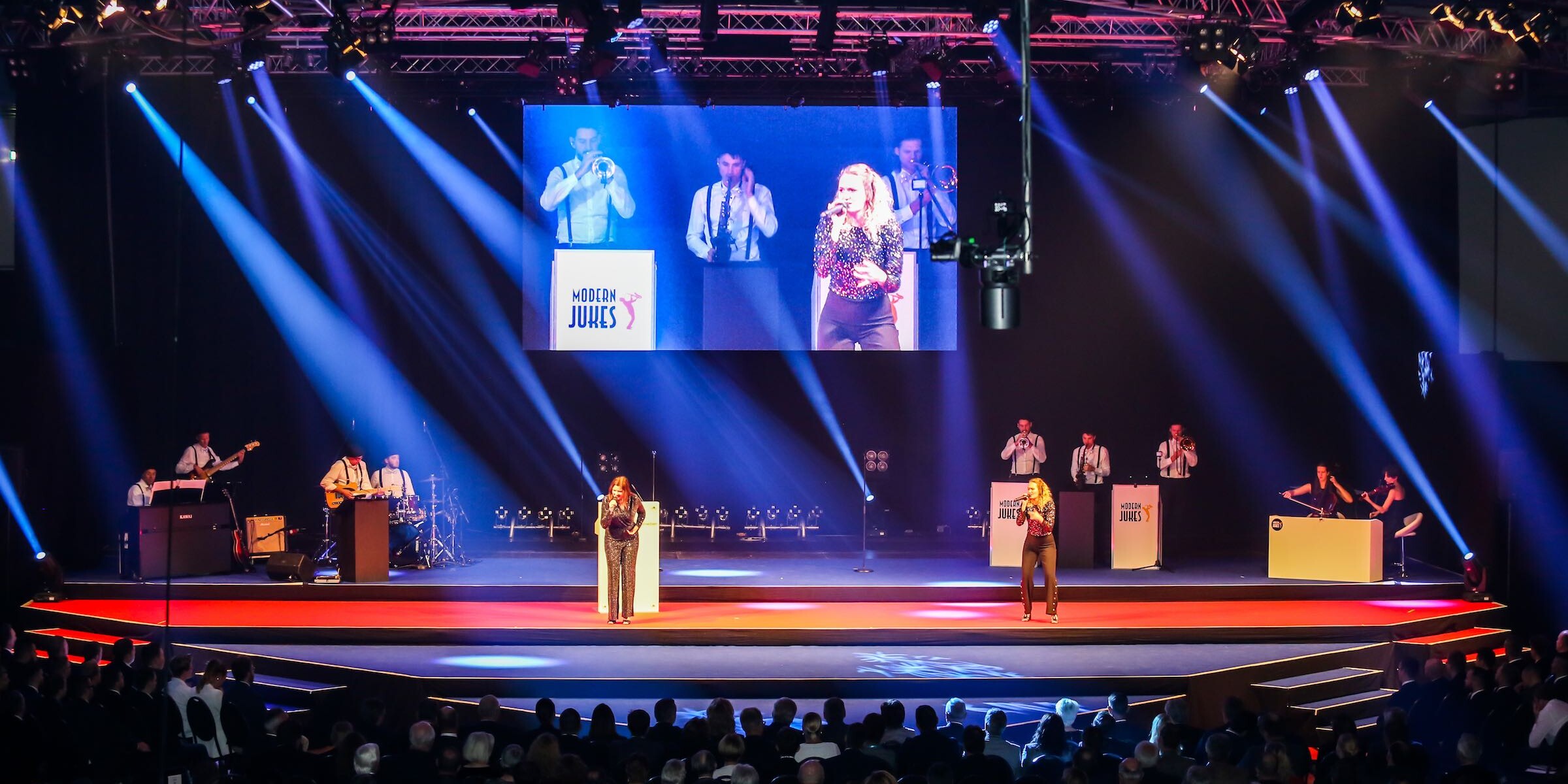 Liveband auf B&uuml;hne mit Lichttechnik und LED-Screen bei einer Veranstaltung