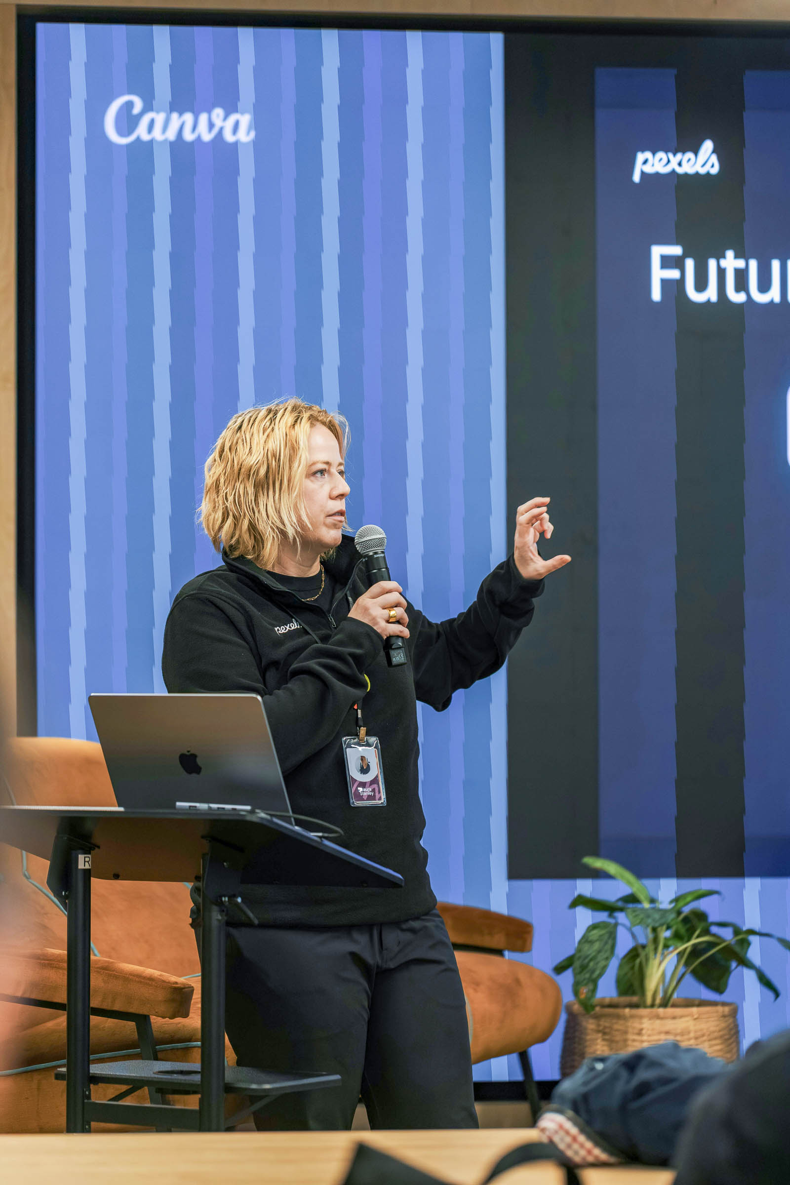 Speakerin auf Bühne mit Mikrofon und Präsentationsdisplay